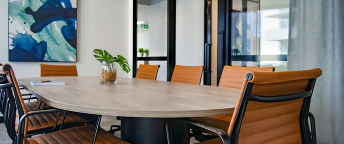 Difusores de aroma para oficinas en México — sala de juntas con mesa ovalada de madera clara, sillas de piel color coñac y luz natural